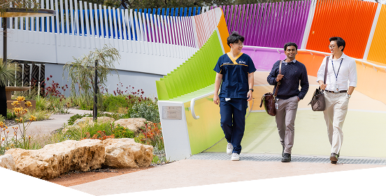 Three medical students walking across a rainbow bridge