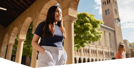 Two female students in front of Winthrop Hall with their bicycles